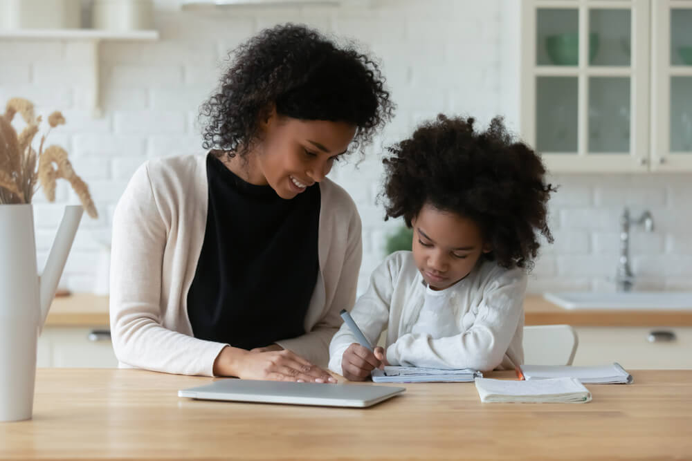 a child being helped by her mother during an homeschooling program